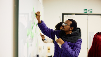 An AfOx student writing on a whiteboard at the AfOx retreat. 