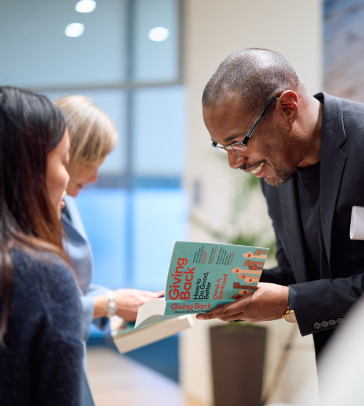 Derek Bardowell signing a copy of his book at a Skoll seminar.