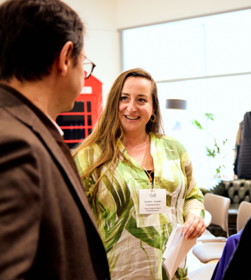 Susanna Kislenko standing in front of red telephone booth smiling and talking to another Skoll Community Convening attendee.