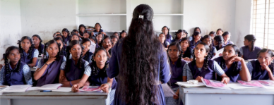 Woman standing in a classroom teaching Indian students part of Eco Femme