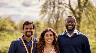  Saransh standing and smiling in a green meadow with the other 2025-26 Skoll Scholars, Luisa and Yousif.
