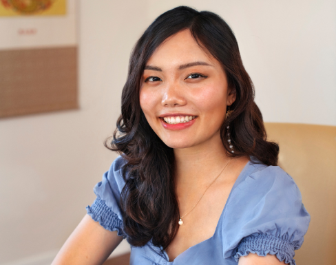 Diana Chao sitting at a desk wearing a light blue top and smiling.