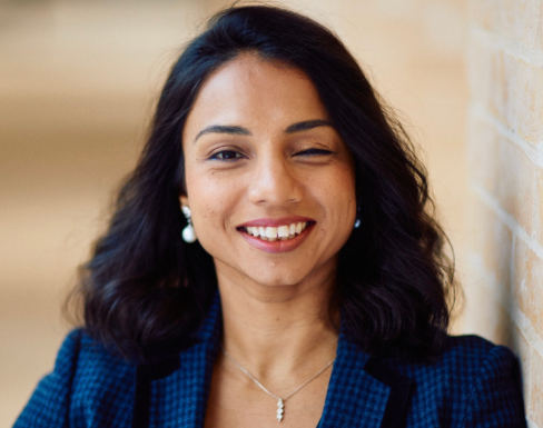 Mahreen Khan standing in the Said hallway wearing a blue suit and smiling. 