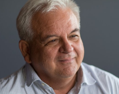 Marc Ventresca smiling and wearing a light grey shirt. 