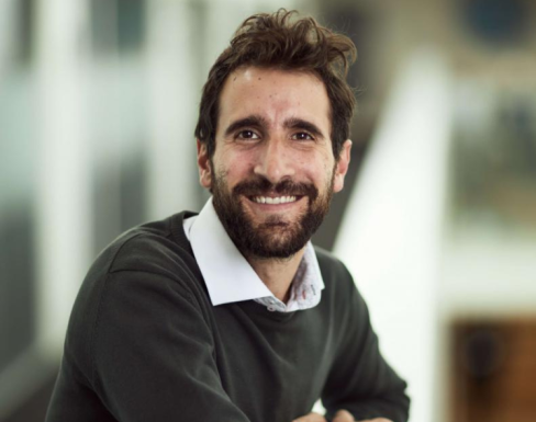 Paulo Savaget standing in the Said hallway wearing a grey jumper and smiling. 