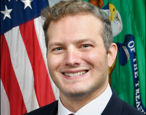 Aaron Bartnick in front of the USA flag smiling. 