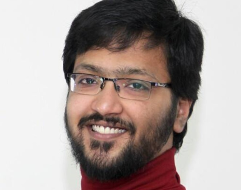 Ahmed Abu Bakr smiling and wearing a red jumper. 