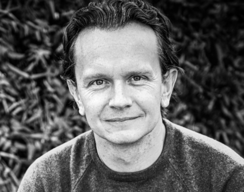 Andy Thornton sitting in front of greenery smiling. 