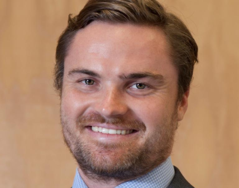 Chris Raine smiling and wearing a suit. 