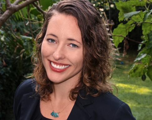 Claire Mongeau smiling, standing against a backdrop of nature. 