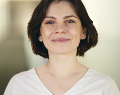 Daniela Gheorghe smiling and wearing a white top.