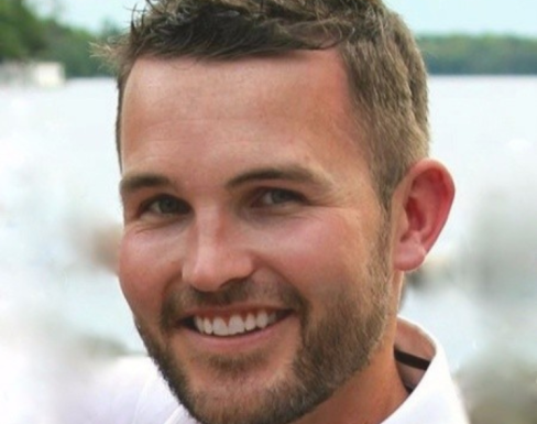 David Damberger stood in front a river and greenery smiling. 