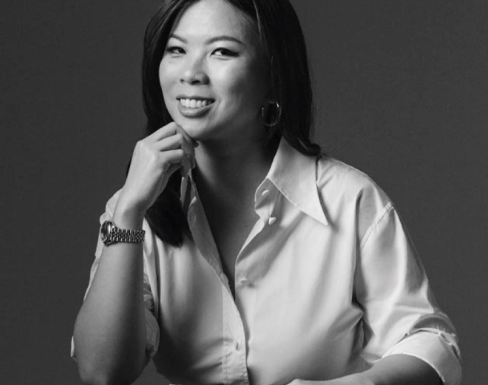 Grace Sai sat at a desk wearing a white shirt and smiling.