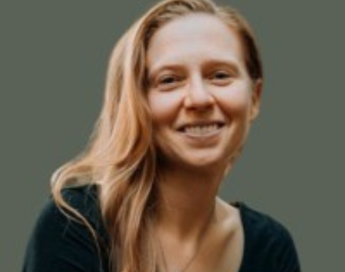 Jessica Lax in front of a teal background, smiling in a black top.
