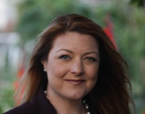 Keely Stevenson stood in front of a natural blurred background wearing a black blazer.