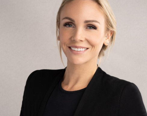 Kjerstin wearing a black suit and smiling.