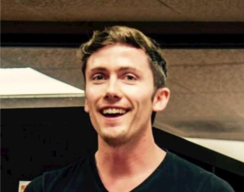 Mark Hlady wearing a black t-shirt and smiling. 