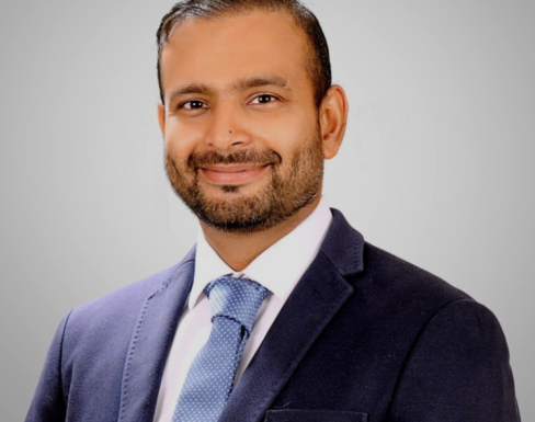 Mohsin Mustafa smiling and wearing a suit. 