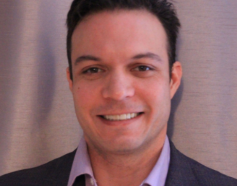 Sean Holt wearing a suit and smiling.