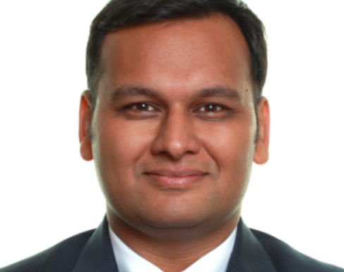 Shubham Anand smiling and wearing a dark grey suit. 