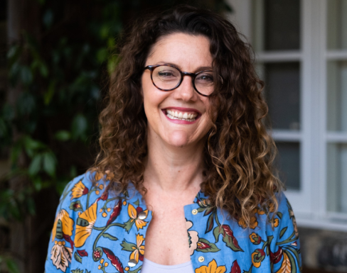 Tasmin Jones wearing a colourful shirt outside a house smiling. 
