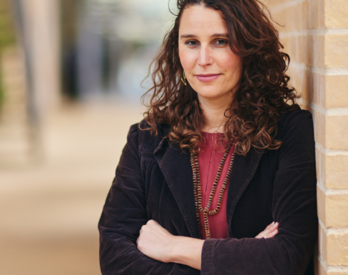 Laura Trajber Waisbich standing in the SBS hallway wearing a black blazer and red top.
