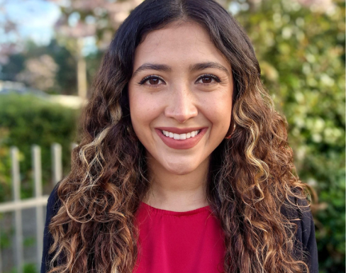 Luisa is smiling and wearing a red top. 