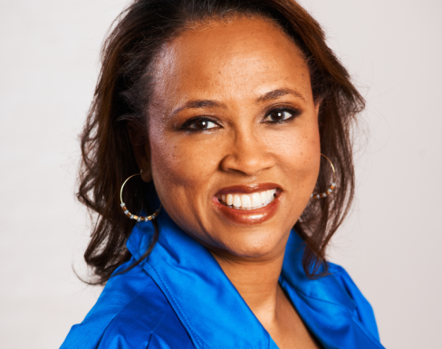 Cheryl is wearing a bright blue shirt and smiling. 