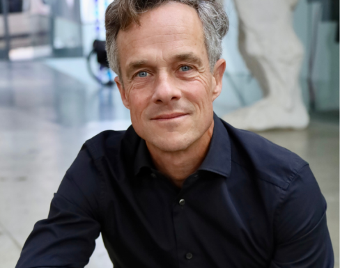 Sebastian is wearing a navy shirt and smiling. 