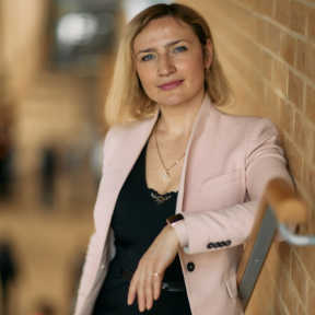 Alona Revko standing on the Saïd stairs wearing a pink jacket. 