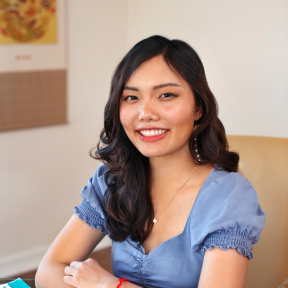 Diana Chao sitting at a desk wearing a light blue top and smiling.
