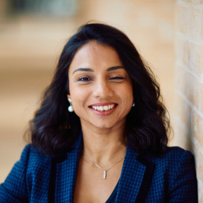 Mahreen Khan standing in the Said hallway wearing a blue suit and smiling. 
