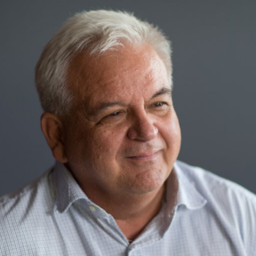 Marc Ventresca smiling and wearing a light grey shirt. 