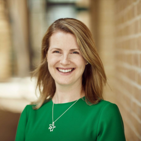 Mary Johnstone-Louis standing in the SBS hallway wearing a green top and smiling. 