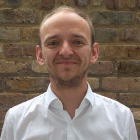 Alex Shapland Howes smiling and wearing a white shirt.