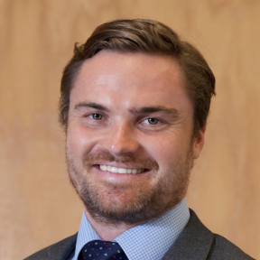 Chris Raine smiling and wearing a suit. 