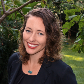 Claire Mongeau smiling, standing against a backdrop of nature. 