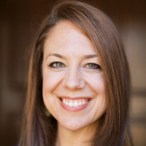 Cynthia Rayner smiling in front of a brown background.
