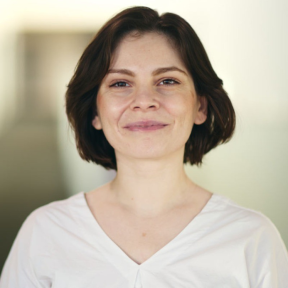 Daniela Gheorghe smiling and wearing a white top.