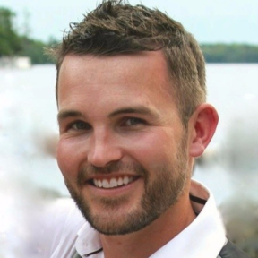 David Damberger stood in front a river and greenery smiling. 