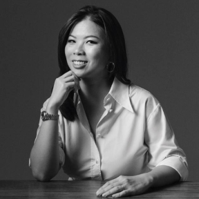 Grace Sai sat at a desk wearing a white shirt and smiling.