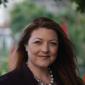 Keely Stevenson stood in front of a natural blurred background wearing a black blazer.