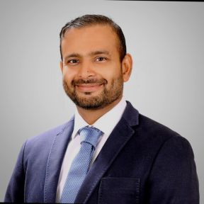Mohsin Mustafa smiling and wearing a suit. 