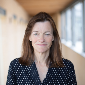 Pippa standing in the Said hallway wearing a black and white top and smiling. 