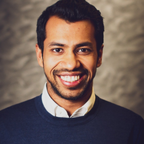Ritesh Singhania wearing a jumper and shirt and smiling. 