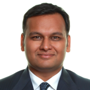 Shubham Anand smiling and wearing a dark grey suit. 