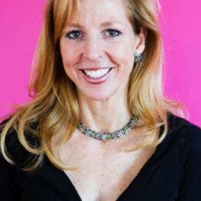 Tara Roth McConaghy smiling in front a bight pink background wearing a black top.