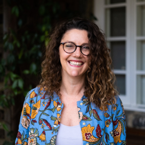 Tasmin Jones wearing a colourful shirt outside a house smiling. 