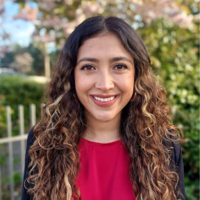 Luisa is smiling and wearing a red top. 